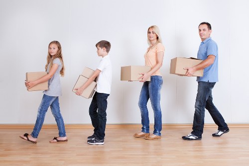 Professional movers lifting heavy furniture with protective equipment