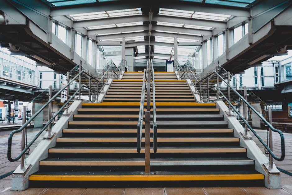 The image depicts a dimly lit indoor staircase made of concrete with eleven visible steps, leading upwards from a dark ground floor. The staircase is enclosed by plain, unfinished concrete walls, and 